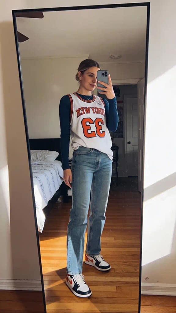 Sporty urban look with layered basketball jersey and denim